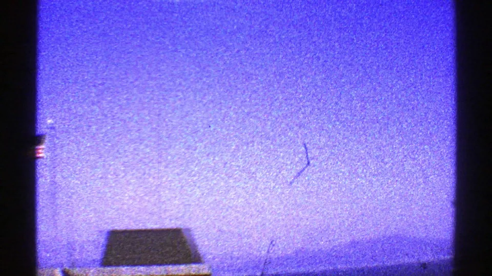 1969 Arizona 8mm frame with purple-blue sky, dark side framing, a low foreground silhouette, and visible dust or scratch marks.
