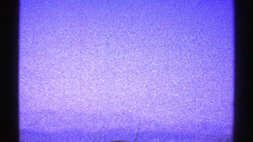 A soft, grainy view of purple-blue sky and faint desert horizon, marked by vertical scratches in the 8mm scan.