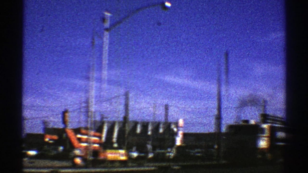 1969 Arizona street view with trucks, cars, roadside signs, utility poles, and a tower in bright daylight.