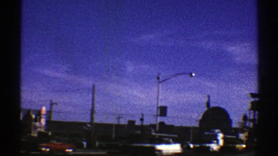 1969 Arizona 8mm view of a roadway with cars, streetlights, a domed structure, signs, and low buildings.