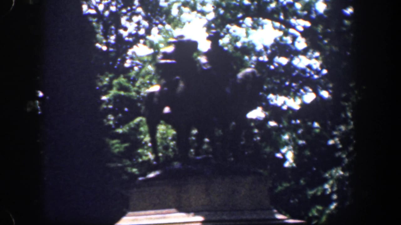 1961 Baltimore home-movie frame with a dark, tree-framed monument or statue area before the stadium view.