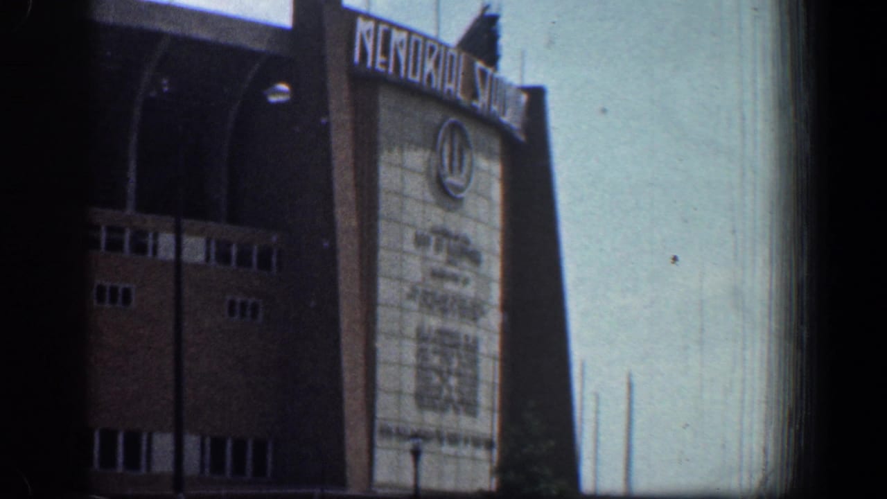 Baltimore Memorial Stadium facade in 1961, showing white rooftop lettering, brick walls, and a circular emblem under clear sky.