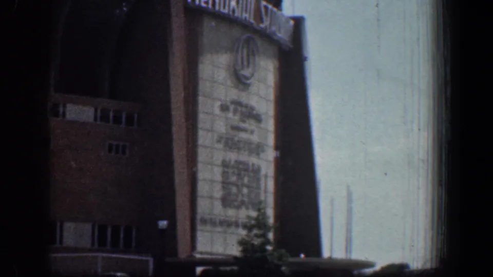 Angled 1961 view of Baltimore Memorial Stadium with white lettering above the facade and shadow crossing the sign panel.