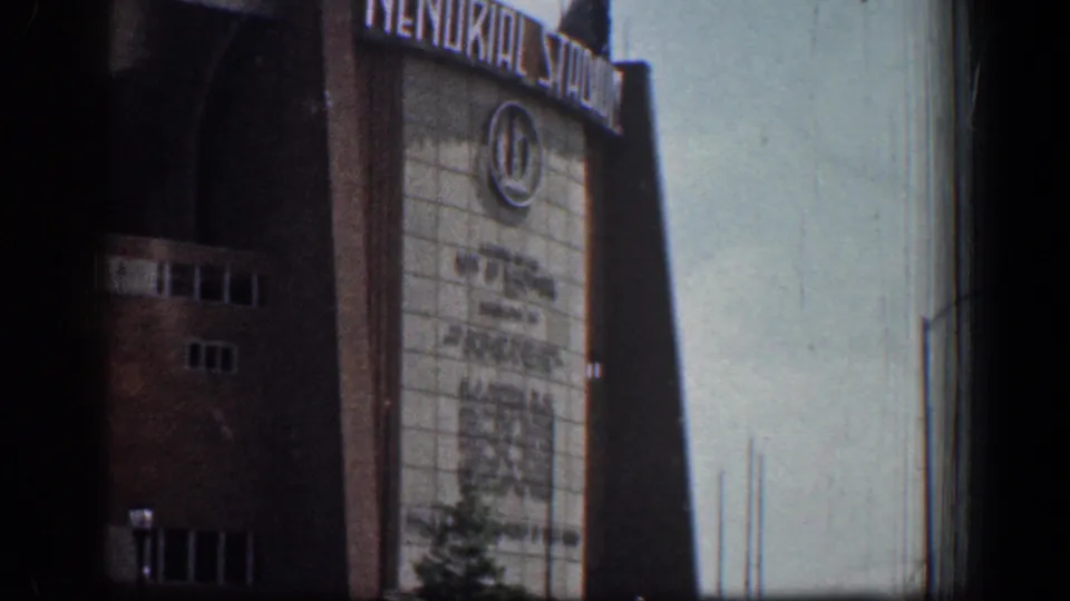 Late-frame 1961 Baltimore view of Memorial Stadium signage, brick exterior, and clear sky with visible 8mm grain.