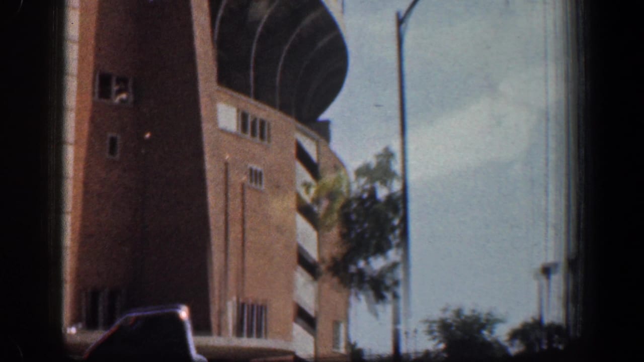 Large brick building with curved facade seen from a car window.