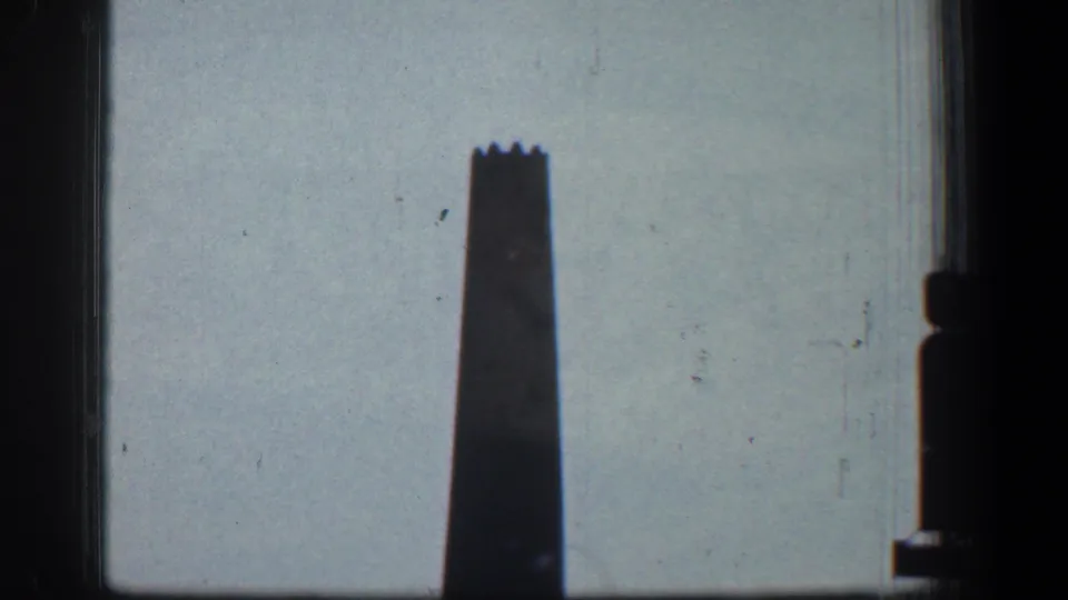 A tall industrial smokestack in Baltimore, Maryland, silhouetted against a pale sky in 1961 8mm footage.