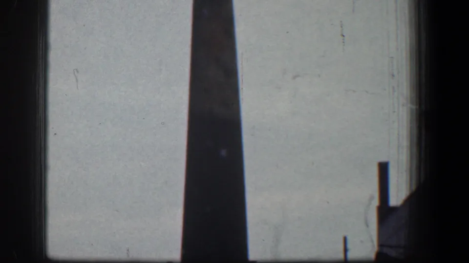 The Baltimore smokestack fills most of the frame, with low industrial edges and a small pole visible near the bottom.