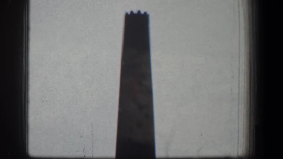1961 Baltimore frame showing a tall chimney with a notched top, softened by 8mm grain and heavy dark edges.