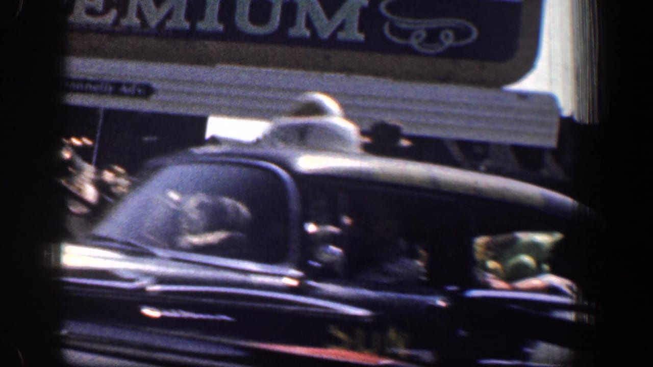 Dark taxi passing beneath a partial storefront sign on a city street.