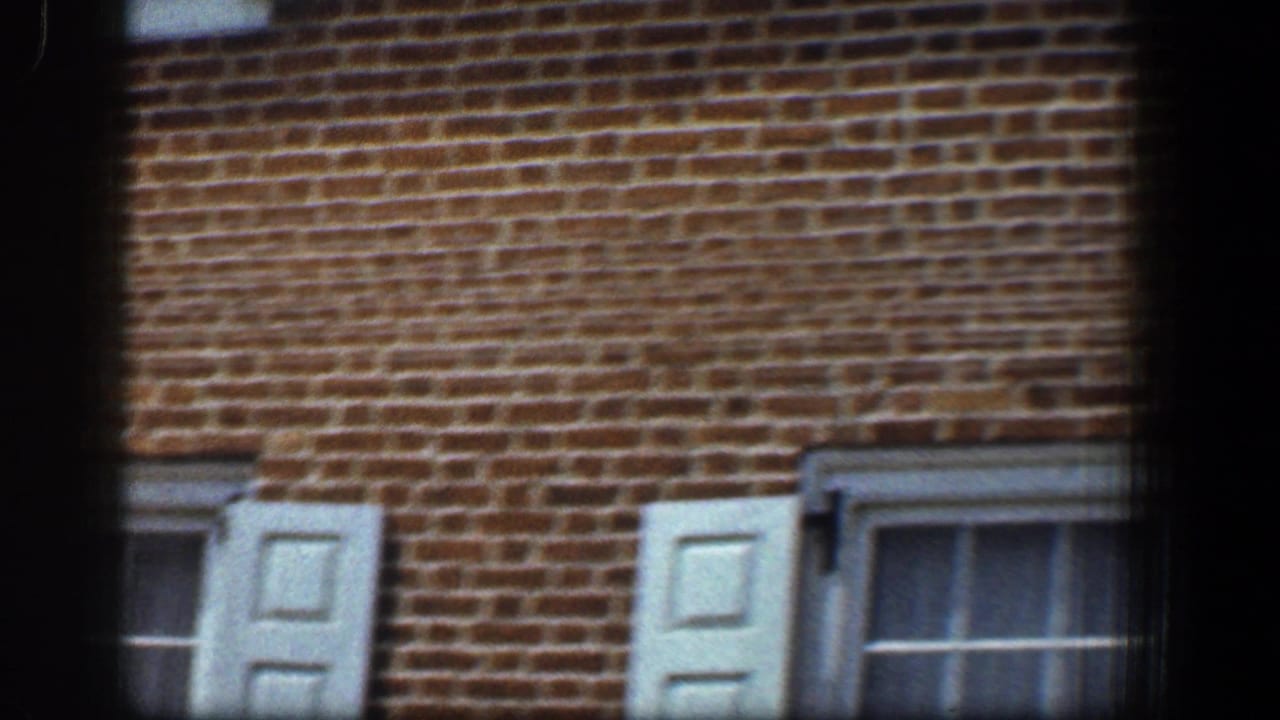 Brick building facade with pale shutters and a partly visible window.