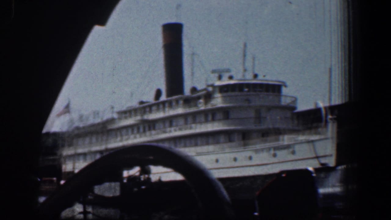 White steamboat seen through a dark car window with a steering wheel in the foreground.