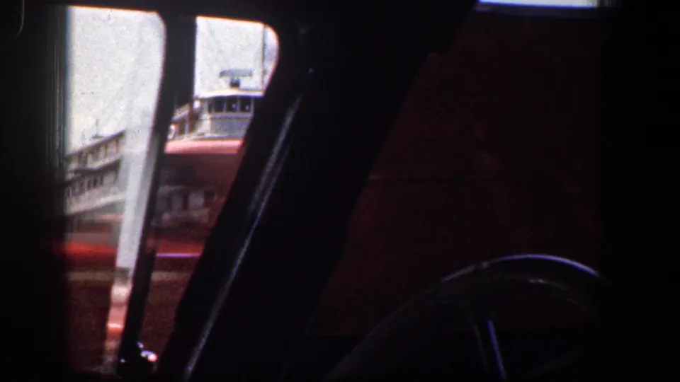 A brief 1961 Baltimore waterfront glimpse shows part of the steamboat through the car window, with the interior in shadow.