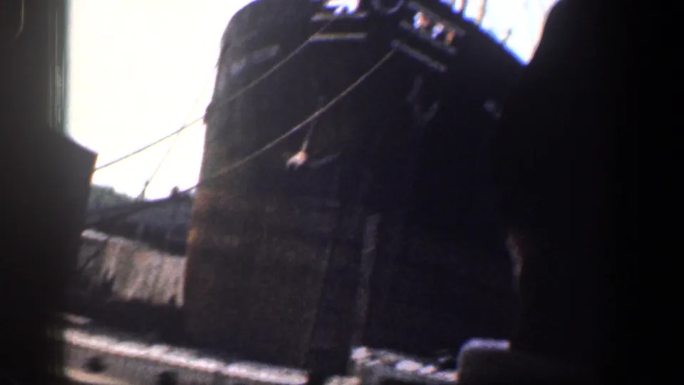 End frame from inside the car, with the steamboat mostly out of view and dockside forms visible in strong contrast.