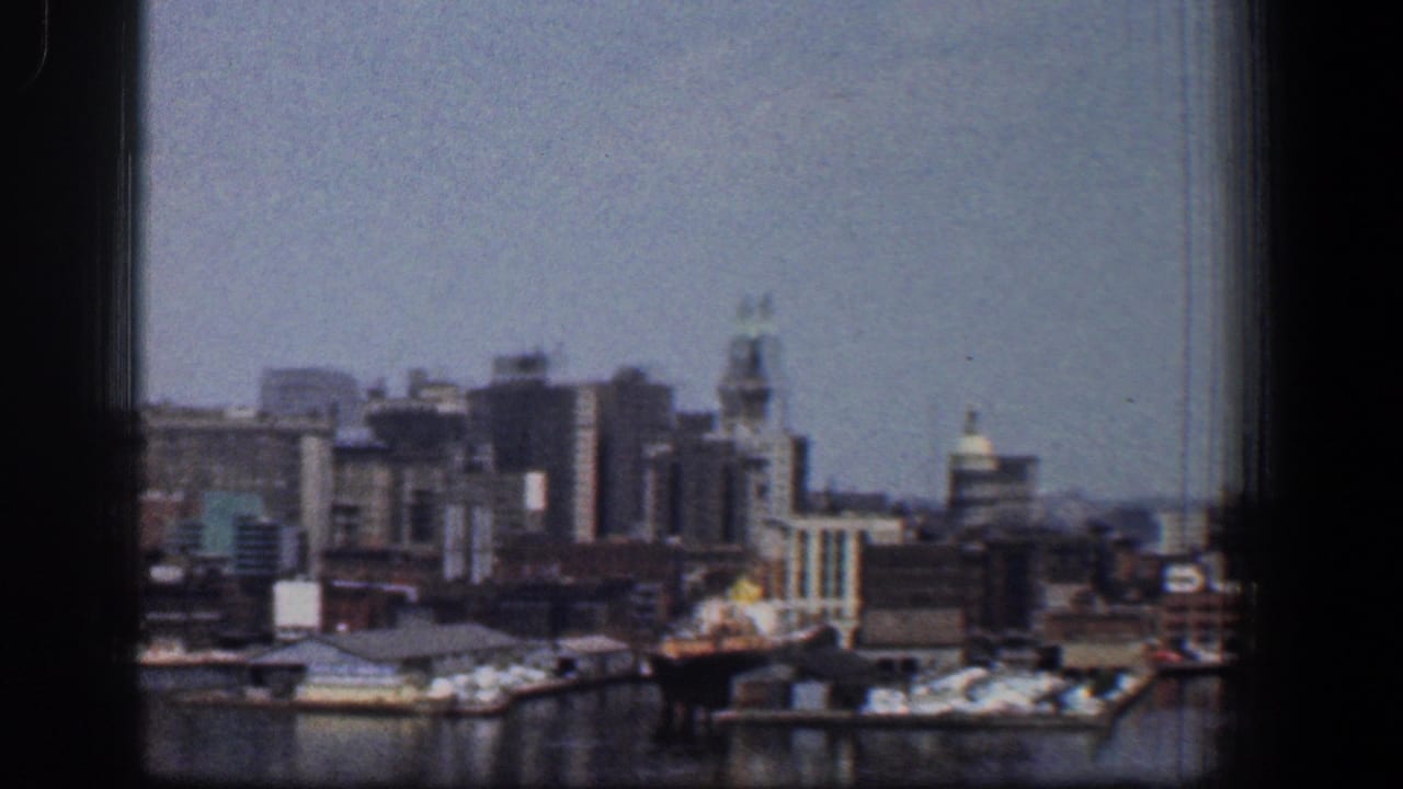 City skyline and waterfront docks viewed across harbor water through a window.
