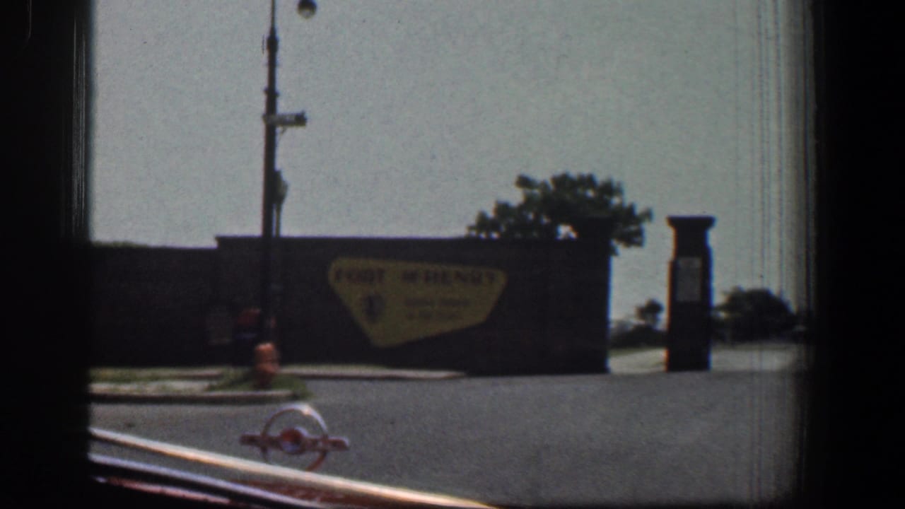 Roadside Fort McHenry sign beside a street, lamppost, hydrant, and dark signpost.