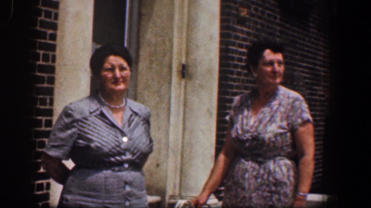 Two adult women standing outside a red brick building near a doorway.