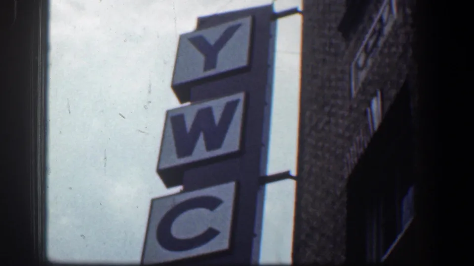 A vertical YWCA sign appears on a Baltimore brick building, with sky and dark building edges in frame.