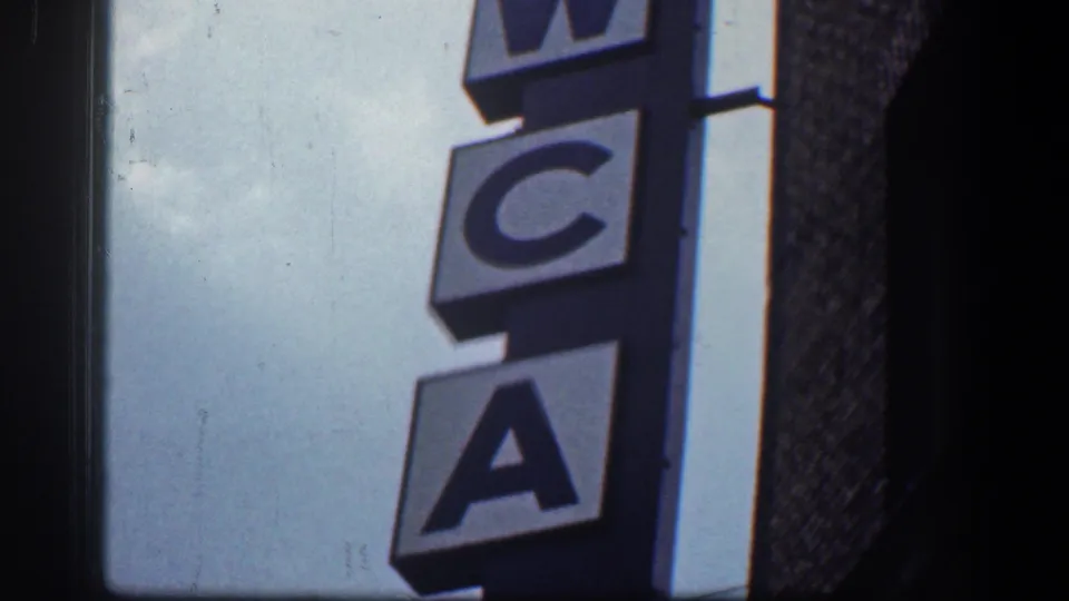 A vertical YWCA sign fills most of the frame, showing large letters against sky and adjacent brickwork.