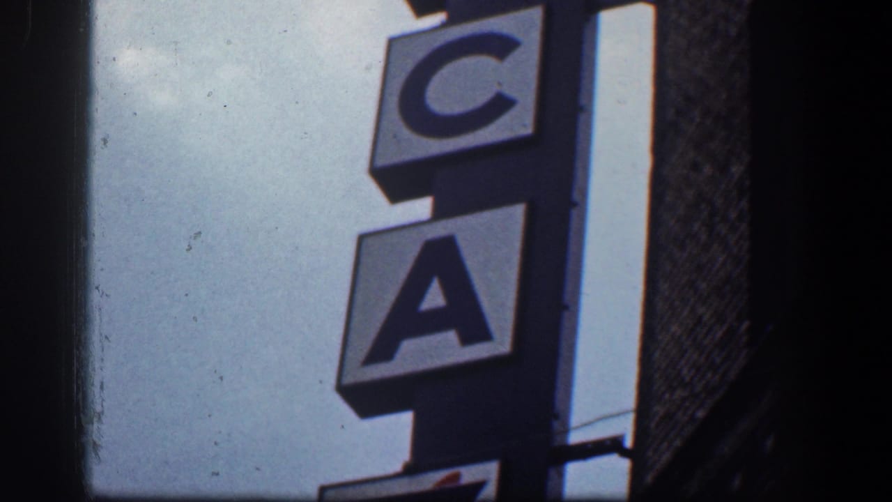 Vertical YWCA sign beside a building edge under a bright sky.