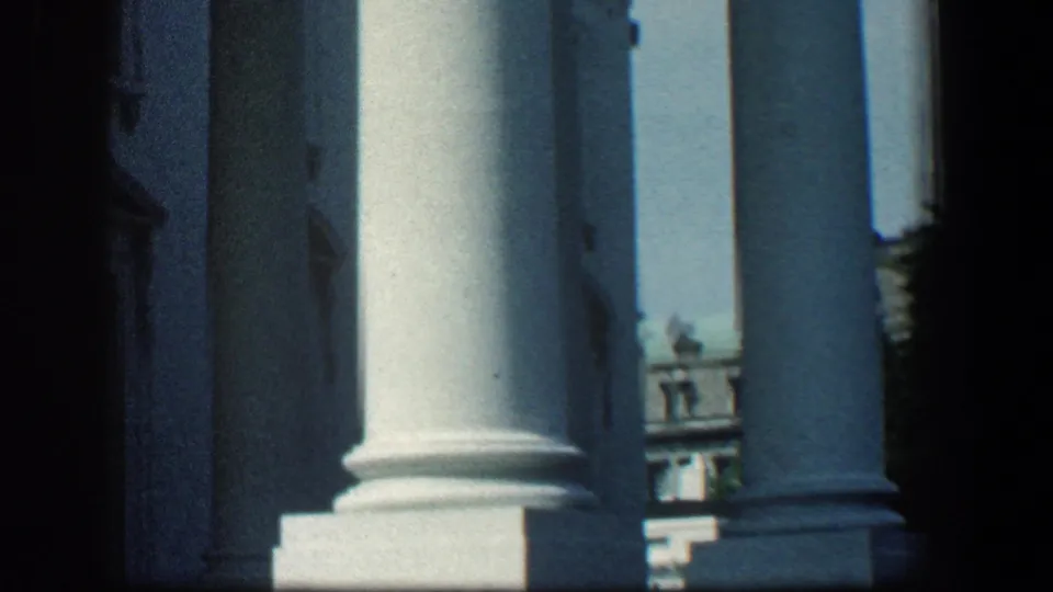 1961 Baltimore 8mm frame showing tall white columns and a classical building exterior from a low, shaded angle.
