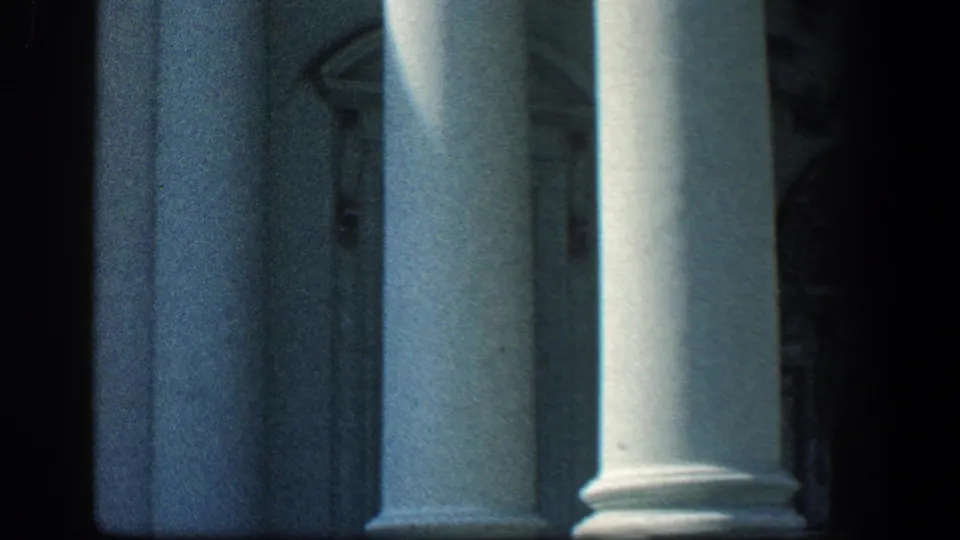 1961 Baltimore frame with several white columns filling the view and deep shadows across the building behind them.