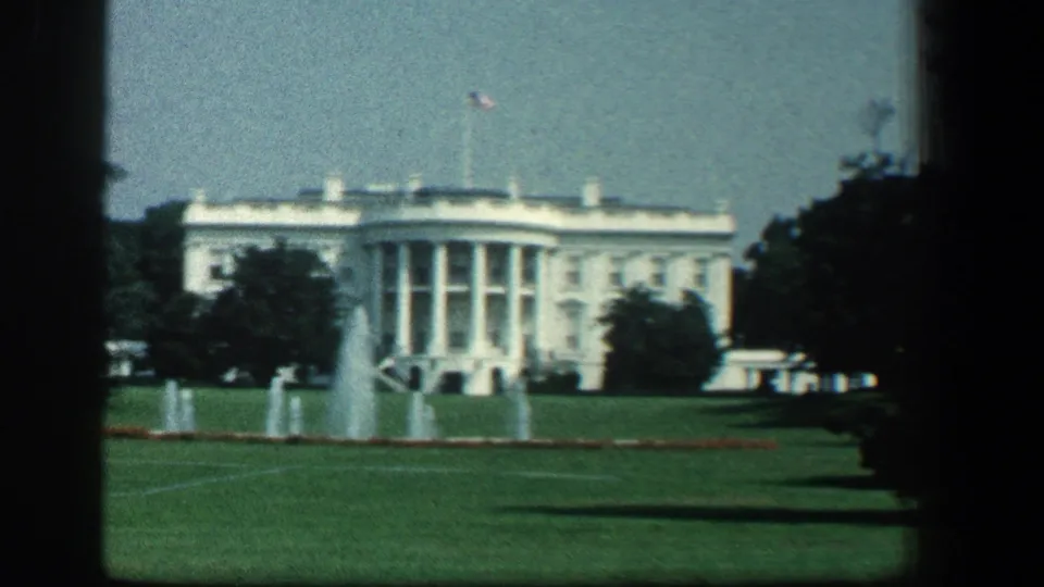The White House exterior appears across a green lawn with fountains in the foreground, filmed in soft 8mm color.