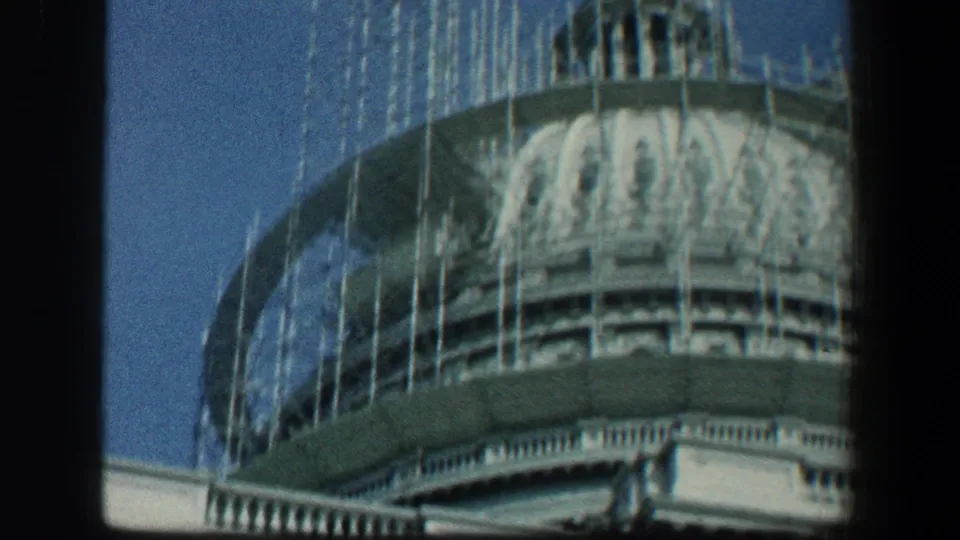 A dome or cupola section of the Baltimore building appears with scaffolding and pale architectural trim under blue sky.