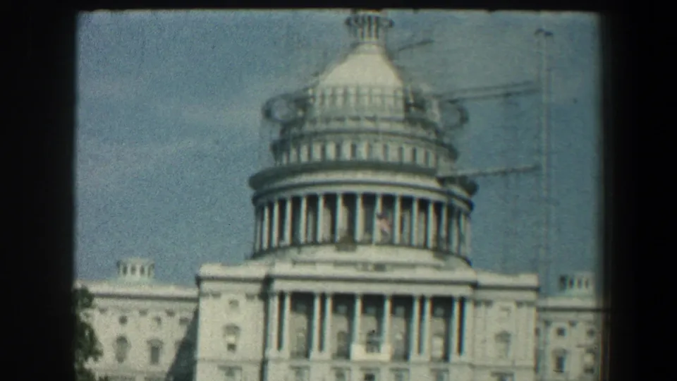A cropped 1961 home-movie view of the U.S. Capitol dome and front facade, with apparent scaffolding visible near the dome.