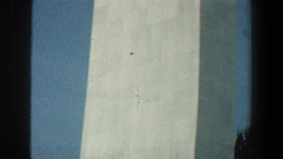 Close 8mm view of pale tower planes and deep vertical shadow, with blue sky behind the structure.