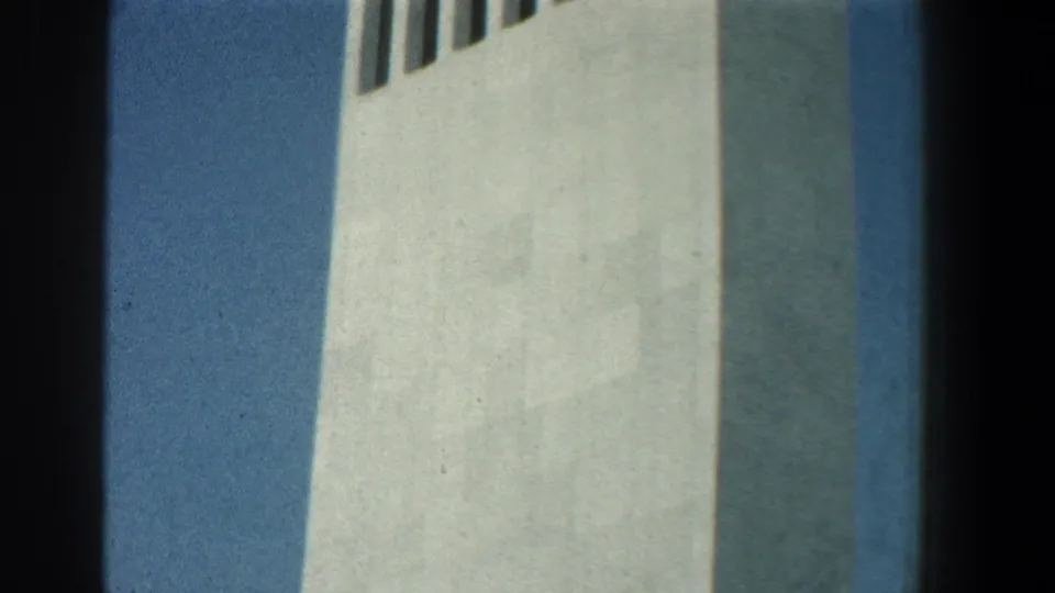 1961 Baltimore frame showing the lower side of a white tower, with narrow vertical openings visible near the top of the view.