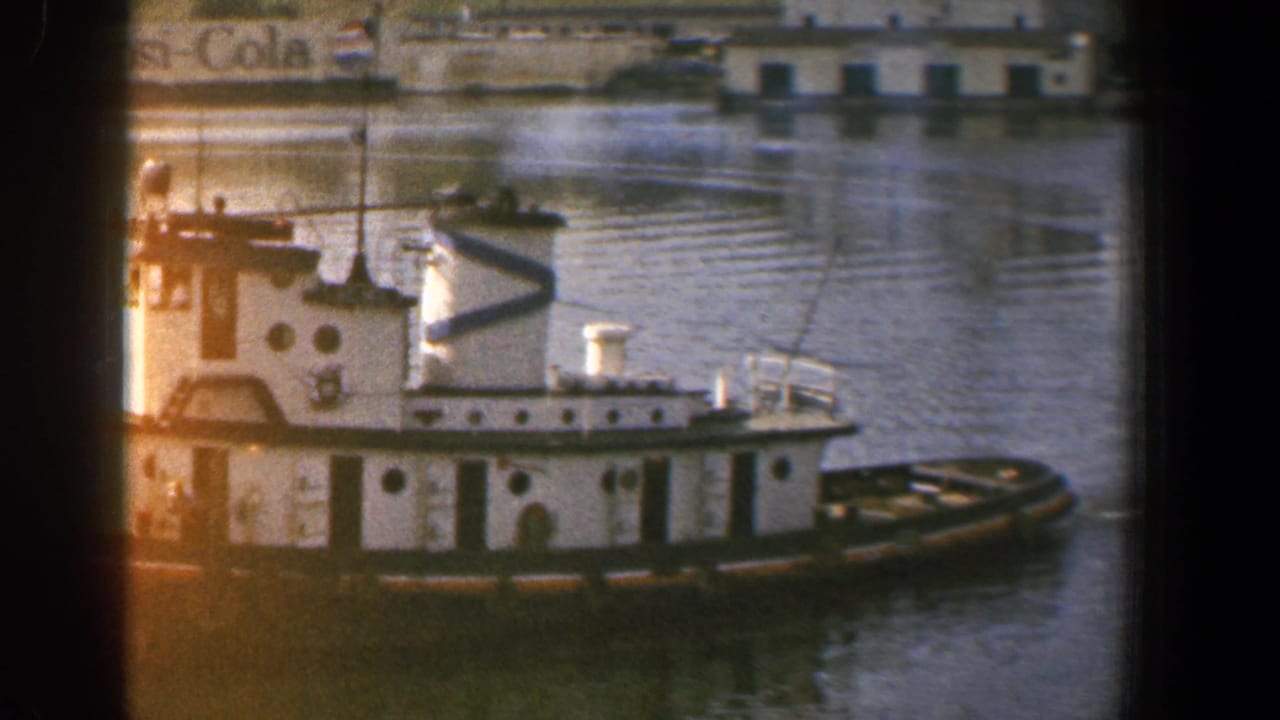 White tugboat in Baltimore harbor, with crew aboard, calm water, and a visible Pepsi-Cola sign behind it.