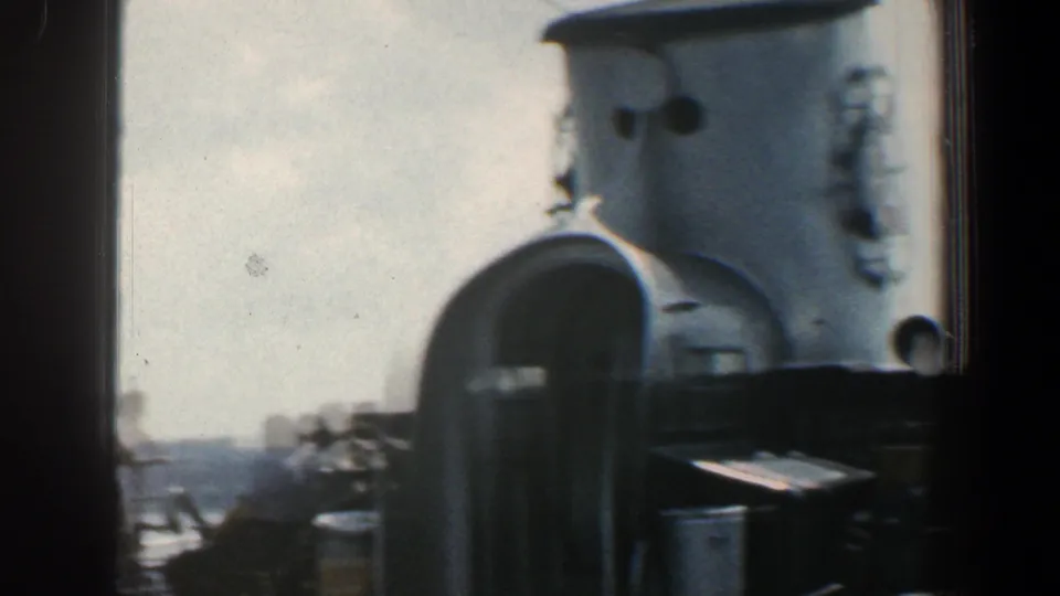 1961 shipboard harbor footage showing the smokestack, railings, deck surfaces, and distant waterline.
