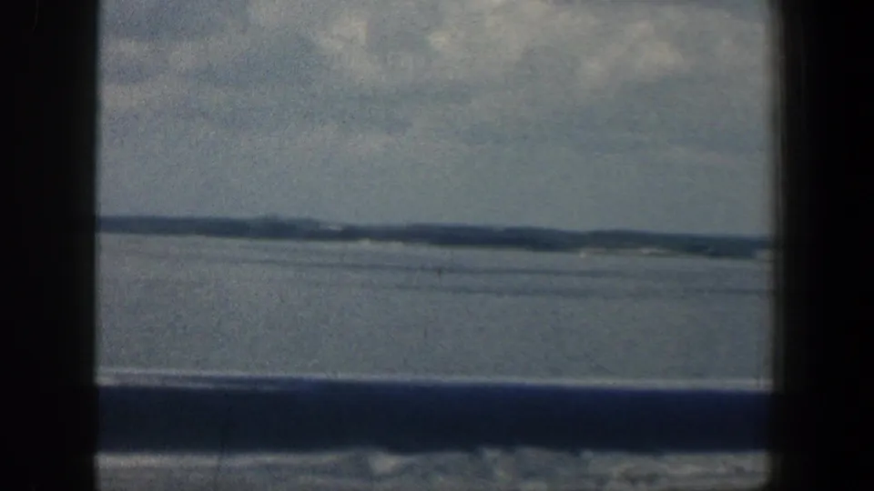 1961 Baltimore-area home-movie view of open water under cloudy sky, framed by dark window or railing edges.