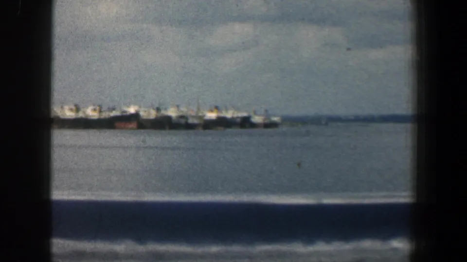 Baltimore-area 1961 home-movie view of grouped boats on water, partially obscured by dark window or railing framing.