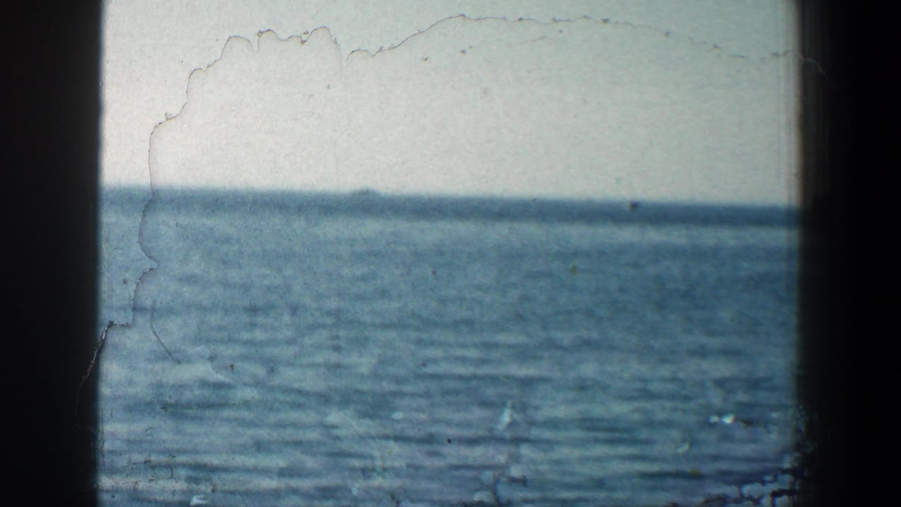 Calm blue water and horizon seen through dark film frame edges.