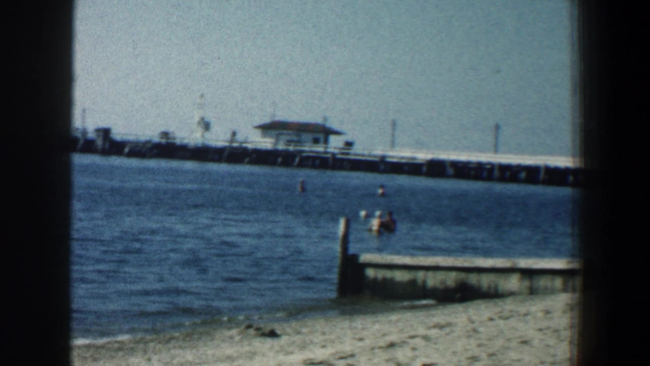 Pier and waterfront seen across the water with a small dock at the right.