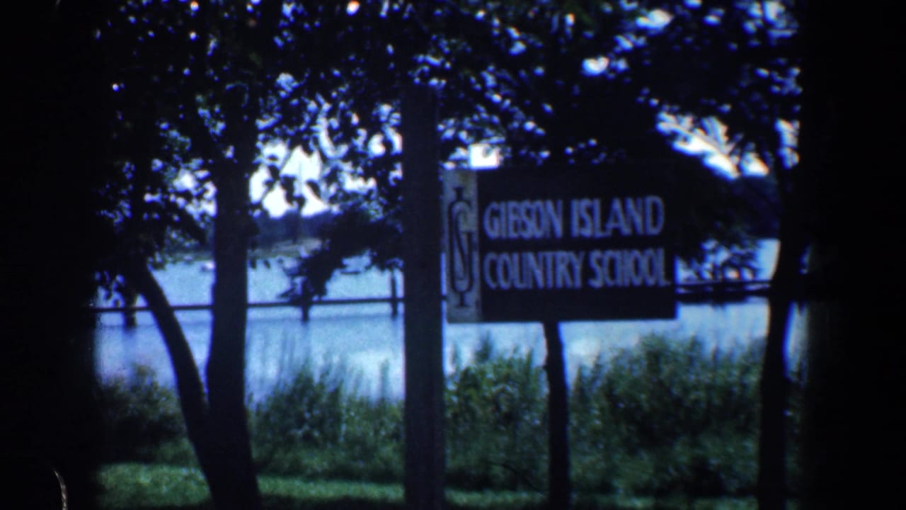 Gibson Island Country School sign beside trees with water in the background.