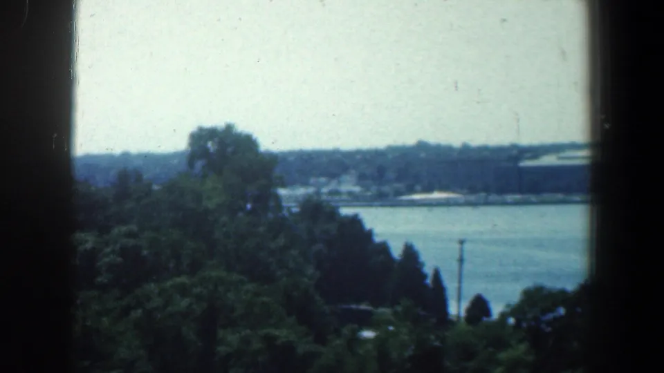 1961 Baltimore-area 8mm frame looking over treetops toward a lake or broad waterway in the distance.