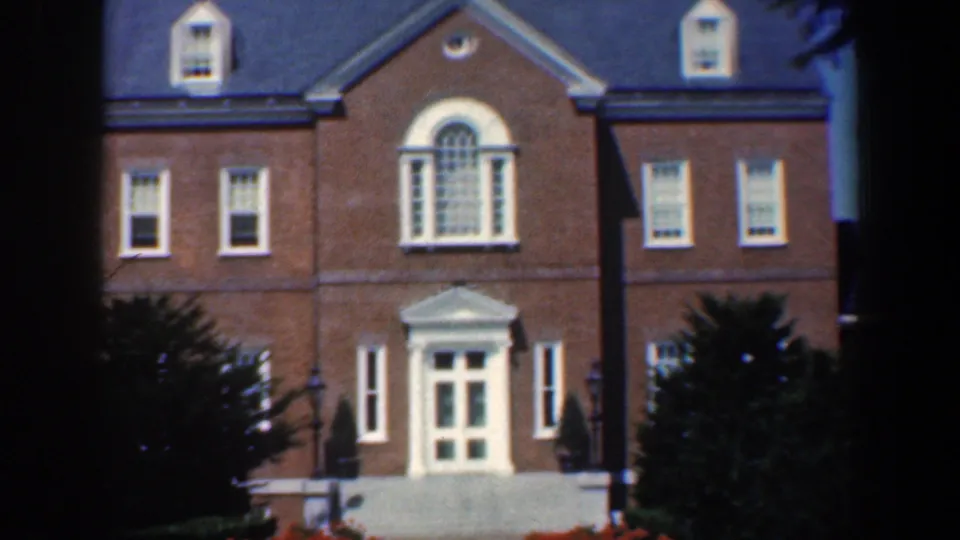 1961 Maryland 8mm frame showing a closer visitor view of the brick building front and landscaped entrance.