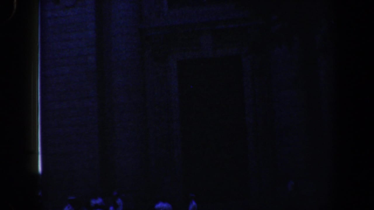 Nighttime 8mm view of a Baltimore church facade with faint figures gathered below the entrance area.