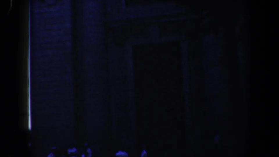 Nighttime 8mm view of a Baltimore church facade with faint figures gathered below the entrance area.