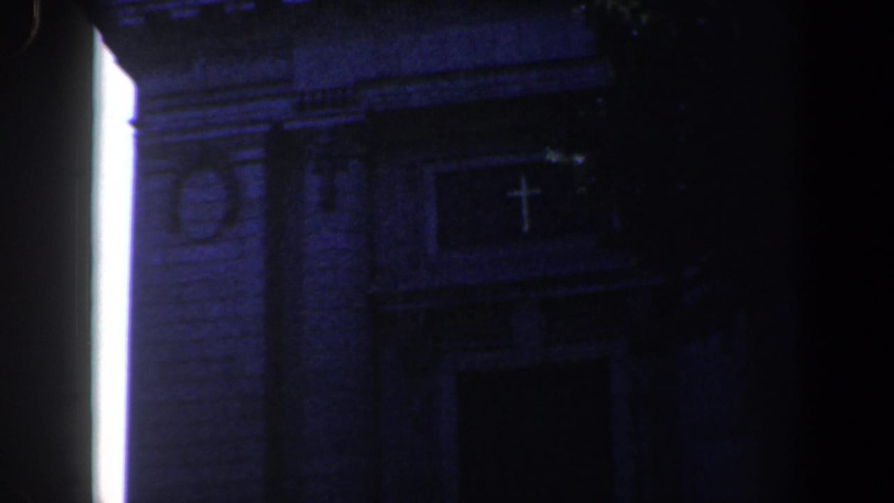 Low-angle church facade partly obscured by tree shade and dark frame edges.