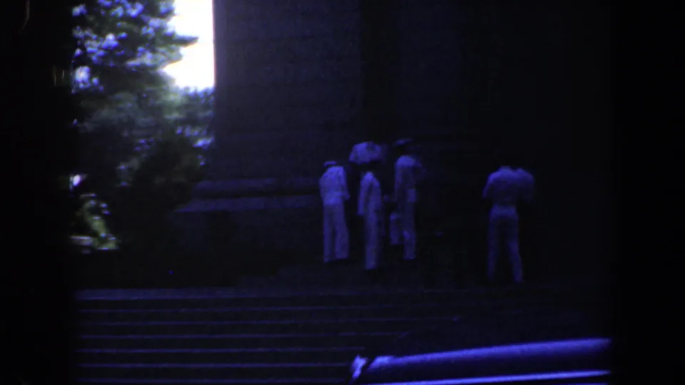 Several visitors in light shirts stand on broad stone steps in a dark, blue-cast 1961 Baltimore 8mm frame.