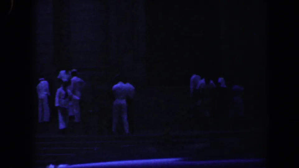Shadowed 8mm frame from Baltimore in 1961 with people gathered on stone steps below a large masonry structure.