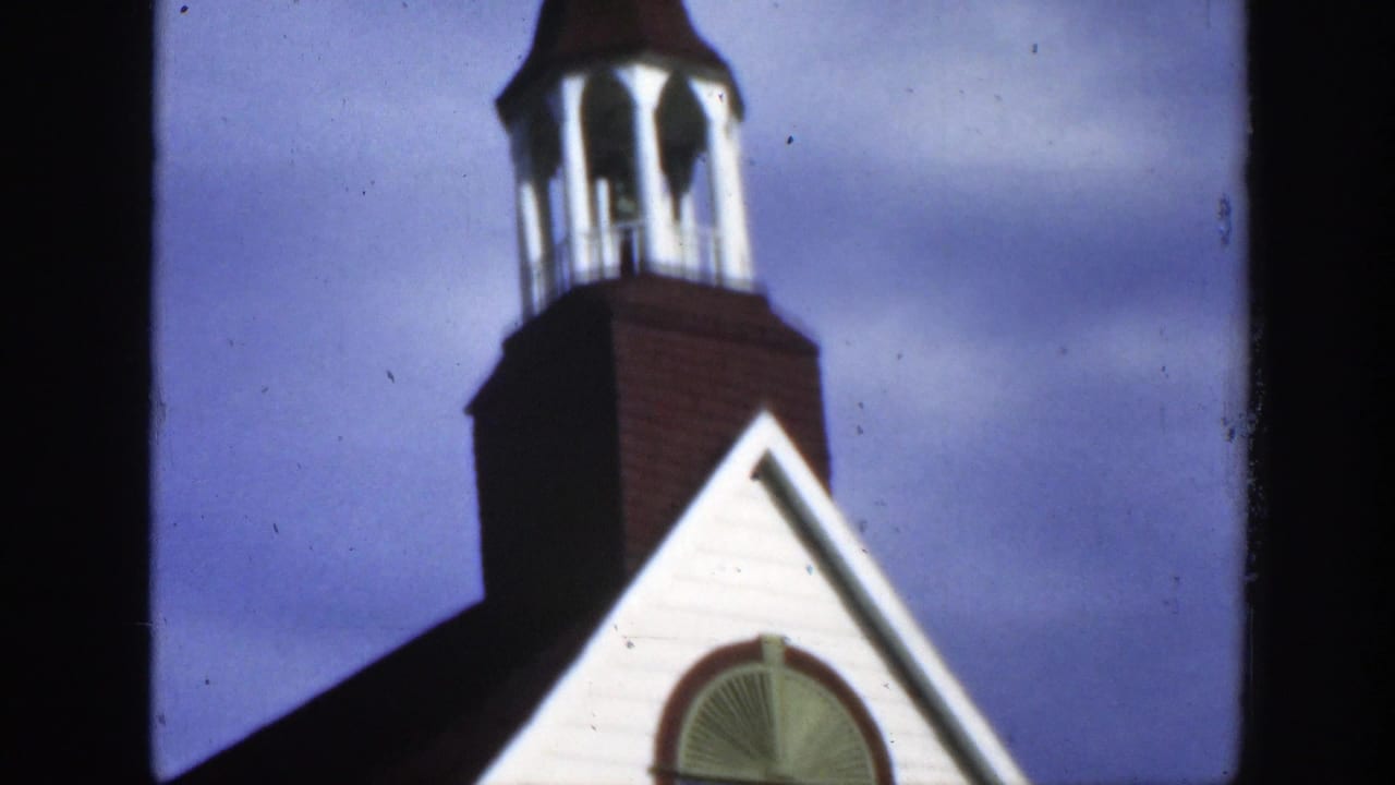 Low-angle view of a brown and white church bell tower against a blue sky.