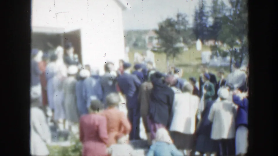 1950 Montreal frame showing a crowd outside the church, with several adults facing the entrance and trees in the background.