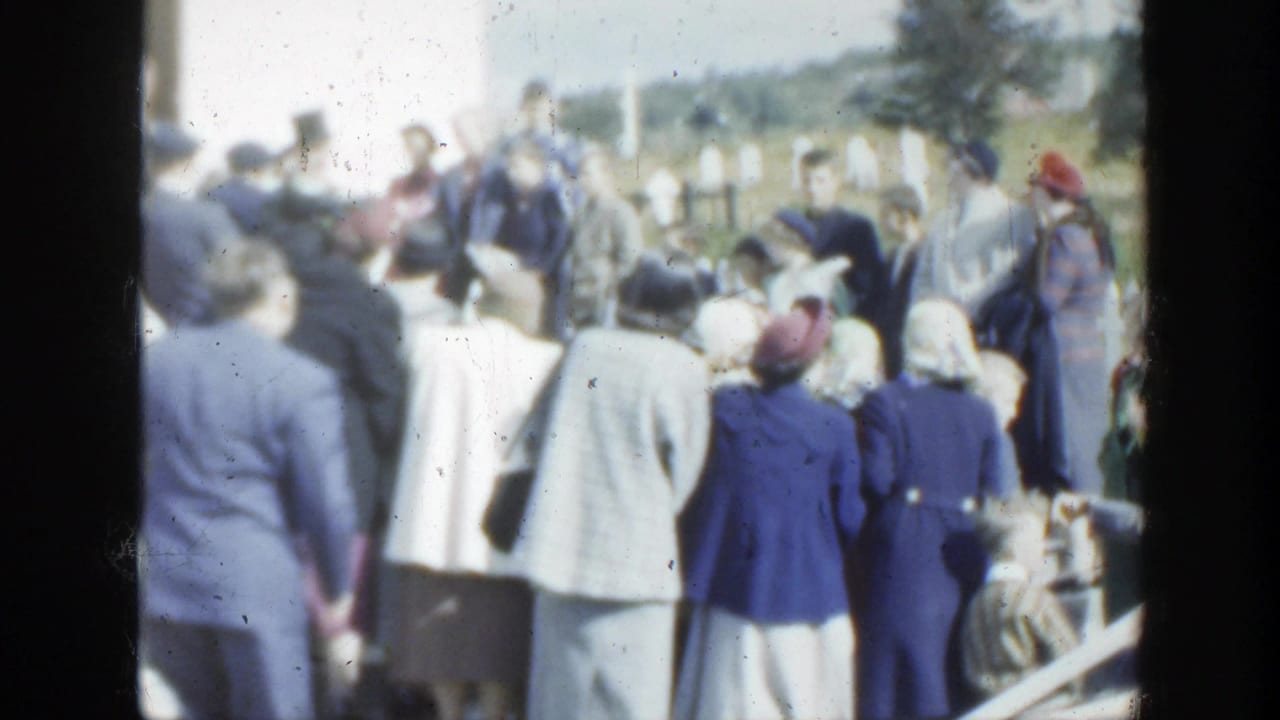 1950 Montreal wedding crowd viewed from behind, with suited men, women in hats, flowers, and trees in the background.