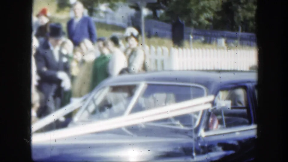 A top-hatted guest and others stand by the ribboned wedding car in the 1950 Montreal home-movie scene.