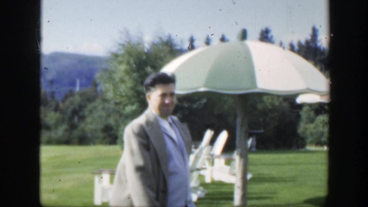 1950 Montreal garden footage shows an adult man turning toward the camera near a green-and-white parasol and white lawn chairs.