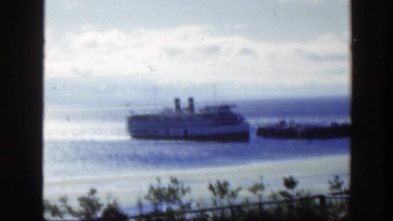 1950 Montreal harbor footage showing a twin-funnel passenger ship near a dark dock structure, seen through a window-like frame.